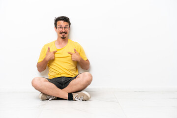 Fototapeta premium Young caucasian man sitting on the floor isolated on white background with surprise facial expression