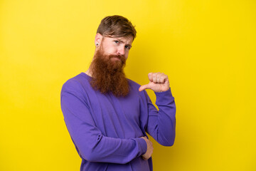 Redhead man with beard isolated on yellow background proud and self-satisfied
