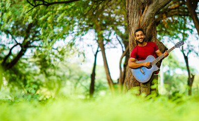 A boy clinging to a tree is playing the guitar