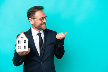 Real estate middle age agent man isolated on blue background pointing to the side to present a...