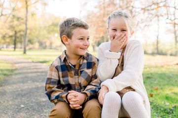 Adorable little siblings gossiping in park on sunny day