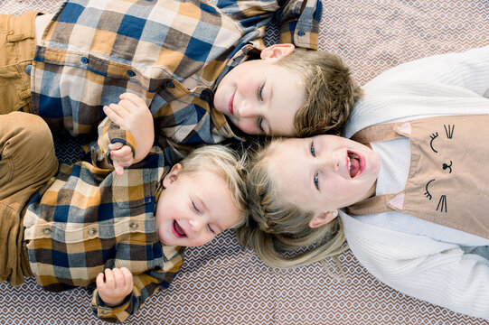 Cute positive little siblings lying on blanket in daylight