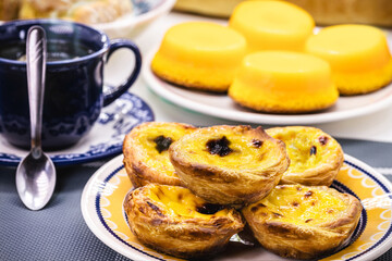 Traditional Portuguese dessert of pastel de nata, and bree de lis in the background, served with coffee, typical Lisbon sweets - obrazy, fototapety, plakaty
