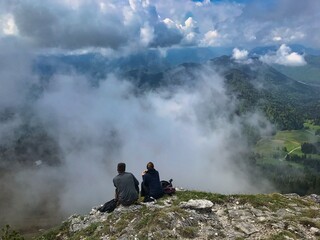 A couple sitting on a rock of a summit and having a rest after a long hike to the top