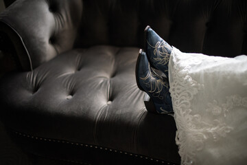 A bride kicking her heels up in blue cowboy boots in her wedding dress on a leather sofa
