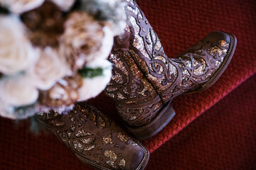 Sparkly cowboy boots with a bridal bouquet in the background