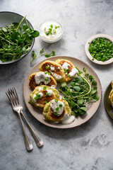 Zucchini fritters, stack of vegetarian zucchini pancakes in a plate, with fresh herbs and sour cream.
