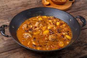 Cheolnt in a frying pan and a plate on a wooden board on the table next to a spoon.