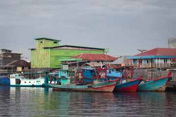 Fototapeta na wymiar Traditional wooden fishing boats moored in Kumai Port in front of some bird nest farms in Borneo