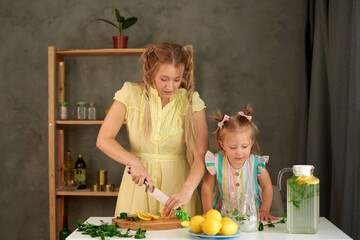 woman make homemade lemonade with fresh yellow lemons and green mint. woman holding knife and...