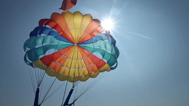 Tandem parasiling high against the clear blue summer sky. Parasailing in the sky on a sunny day, extreme sports