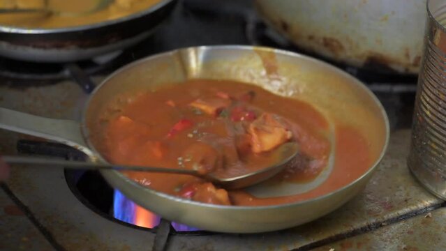 Chicken tikka masala cooking in a pan, traditional popular Indian dish closeup slow motion
