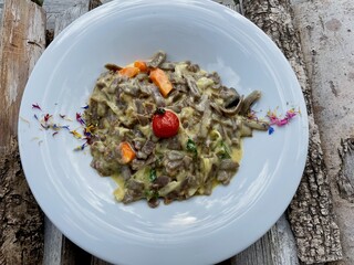 Pizzocheri, typical dish from Grisons, buckwheat pasta, potatoes and cheese served on white ceramic plate.