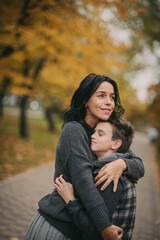 Fototapeta premium happy family: mother and child cuddling on autumn walk in nature outdoors