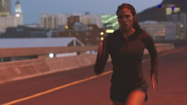Woman training, exercise and workout or running at night in city for fitness, health and sport taking break. Sports, healthy and motivation with a young runner gym and working out in urban bridge