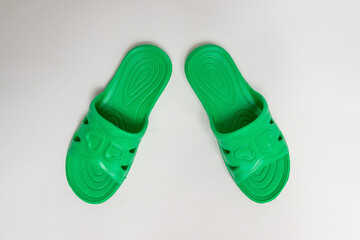 Green, rubber slippers for a bath on a gray background, viewed at 45 °.