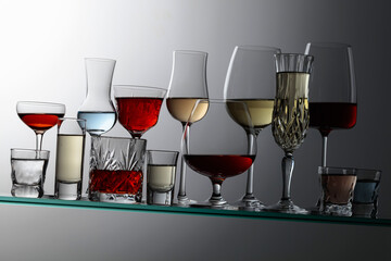Alcoholic drinks on a tilted glass shelf.