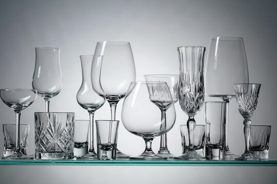 Different Empty Glasses On A Glass Shelf.