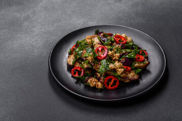 A salad of baked aubergine, sweet pepper, garlic, zucchini and parsley in a black plate
