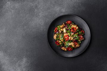 A salad of baked aubergine, sweet pepper, garlic, zucchini and parsley in a black plate
