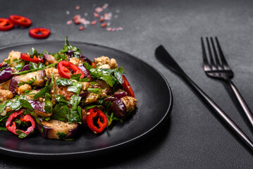 A salad of baked aubergine, sweet pepper, garlic, zucchini and parsley in a black plate