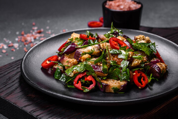 A salad of baked aubergine, sweet pepper, garlic, zucchini and parsley in a black plate