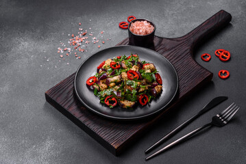 A salad of baked aubergine, sweet pepper, garlic, zucchini and parsley in a black plate