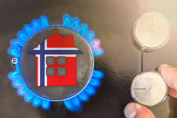 Heating season or gas use in Norway. Concept, model of a house stands near the flame of a gas...