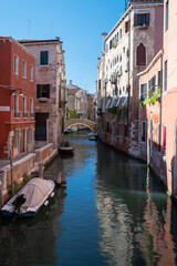 Fototapeta na wymiar Vue d'un canal à Venise, Italie, avec un pont qui se reflete dans l'eau dans une vue pittoresque et typique pour les voyage des touristes.