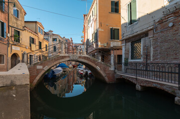 Fototapeta na wymiar Vue typique et touristiques des canaux de Venise en Italie avec le pont qui se refletent dans l'eau en effet miroir