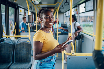 African american woman standing in a moving bus and using a smartphone
