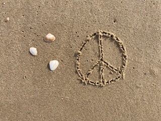 Fototapeta na wymiar on the beach the peace symbol is carved into the smooth sand