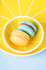 Blue and yellow macaron on a yellow plate and a blue background