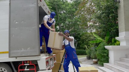 Moving service workers outdoors, unloading boxes and checking list is coming to deliver items to the family moving house.
