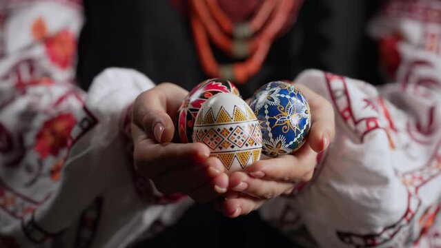 Ukrainian woman holding in hands Easter eggs. Beautiful geometric slavic decoration ornaments. Lady in authentic embroidery vyshyvanka costume. Preparation for Christian holiday.