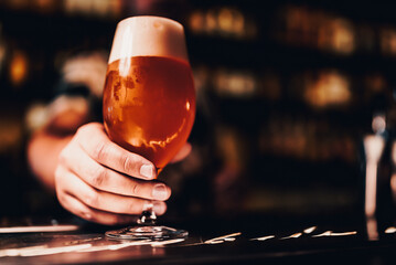 bartender's hand hold full glass of beer in a bar
