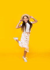 glad teen girl in straw hat jumping on yellow background
