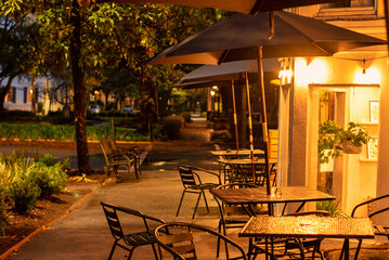 Early evening sidewalk scene in Savannah, Georgia, with empty cafe and restaurant tables - obrazy, fototapety, plakaty