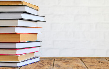 A stack of books on an old wooden table on a light background. Copy space, selective focus.