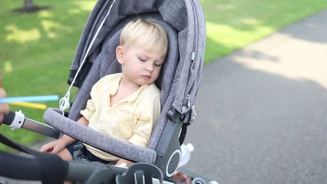 Sweet little sleepy boy  in a stroller