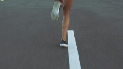 Legs and fast shoes on a road for running, fitness and workout with a woman training for health, sports and exercise. Healthy female runner working out in a city for cardio and endurance from behind