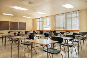 Example of an empty nondescript US High School Classroom with desks, Window and black board.