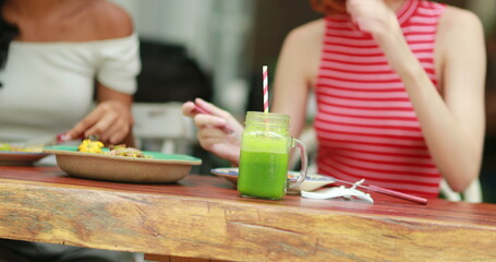 Attractive multiracial friends eating salad and green detox juices