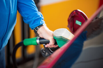 Man refueling his car with gasoline pump. To simulate the high costs of fuel , pollution and energy...