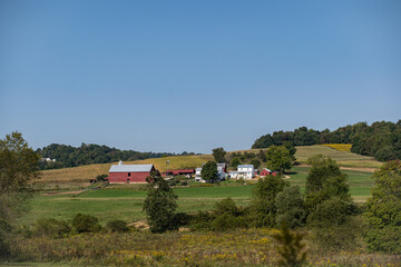 Fototapeta na wymiar Amish farm on a wooded hillside surrounded by fields on a sunny summer day in Holmes County, Ohio