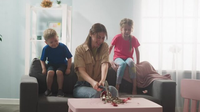 young mother with children breaks piggy bank with hammer with money in form of pig, money box doit