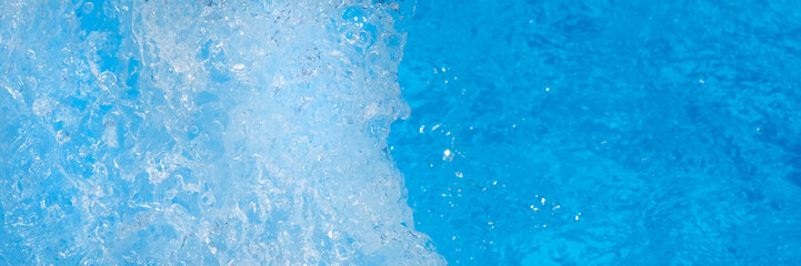 Surface of blue swimming pool water with light reflection, splashes and waves. Texture of...
