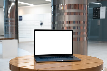 Laptop with white screen in business office or shopping mall. Empty copy space, blank screen mockup. Soft focus laptop with interor background. Travel, study and office work concept - 527925692