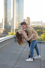 Beautiful happy young loving couple on a surprise date on a Saint Valentine's Day. Romantic date on the rooftop, summertime. Young man and beautiful girl. Newlyweds on honeymoon. Golden hour
