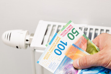 Home heating prices, Increase in energy prices in Switzerland, Heater and Swiss francs held in the hand